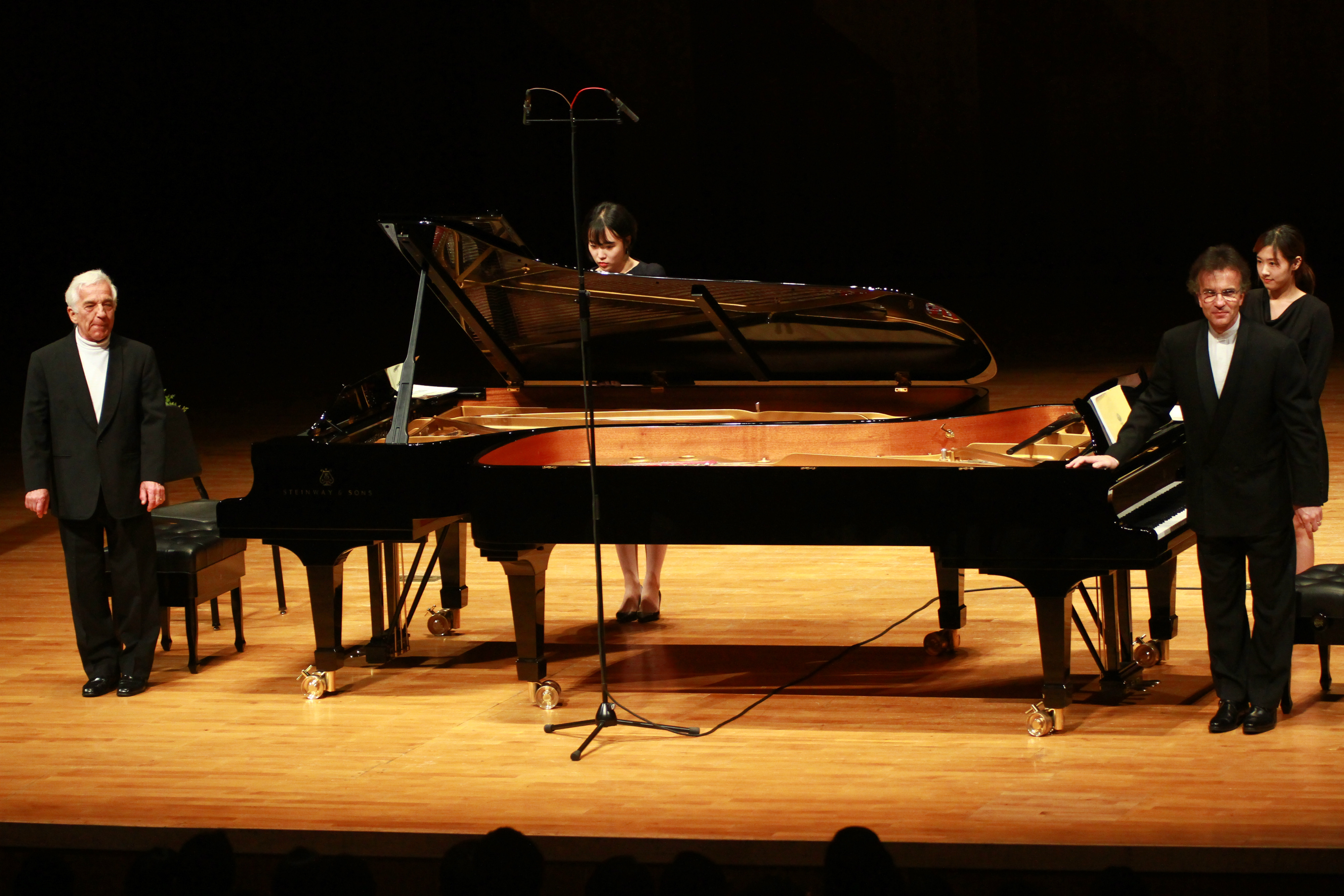 Vovka Ashkenazy and Vladimir Ashkenazy taking a bow beside two grand pianos on a concert stage